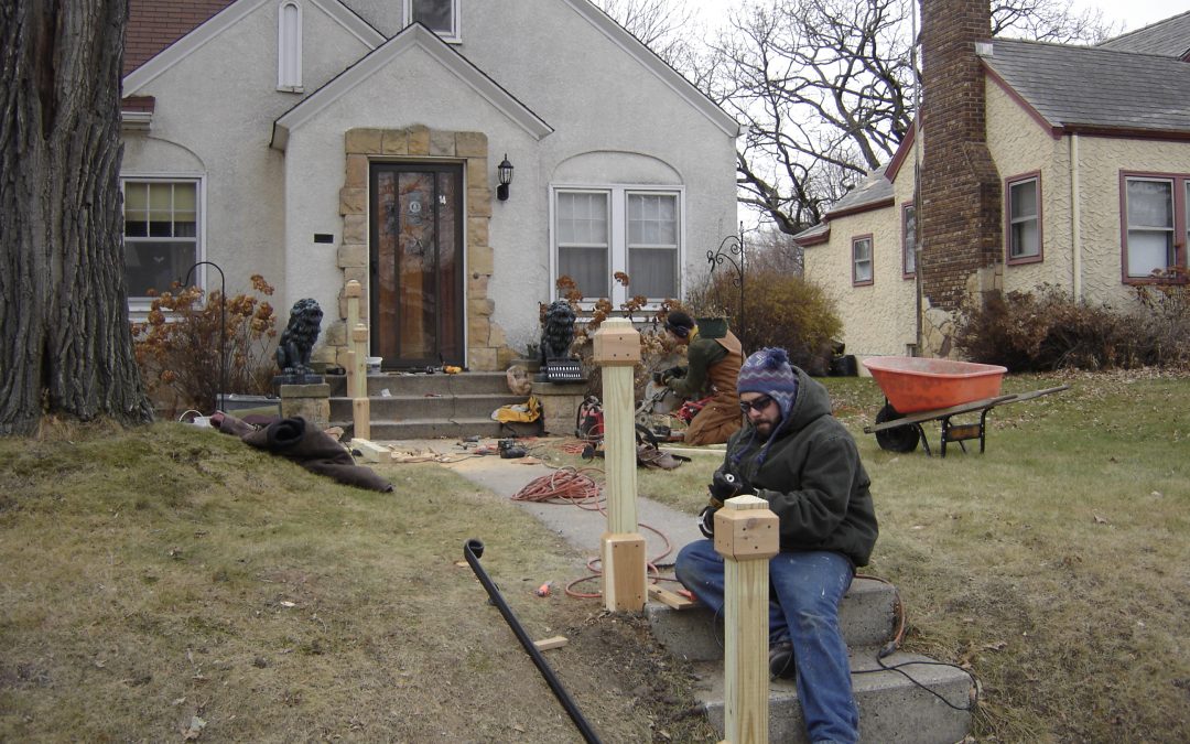 workers installing posts for a railing outside a home