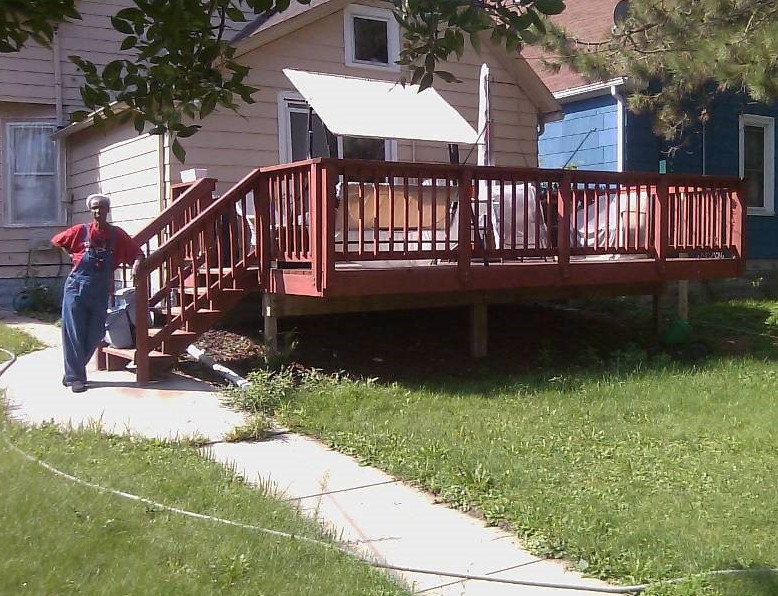 Person standing beside a stairway and ramp to the deck of their home