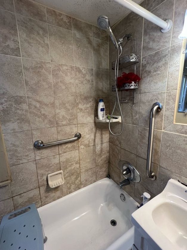 renovated bathroom with shower head and grab bar